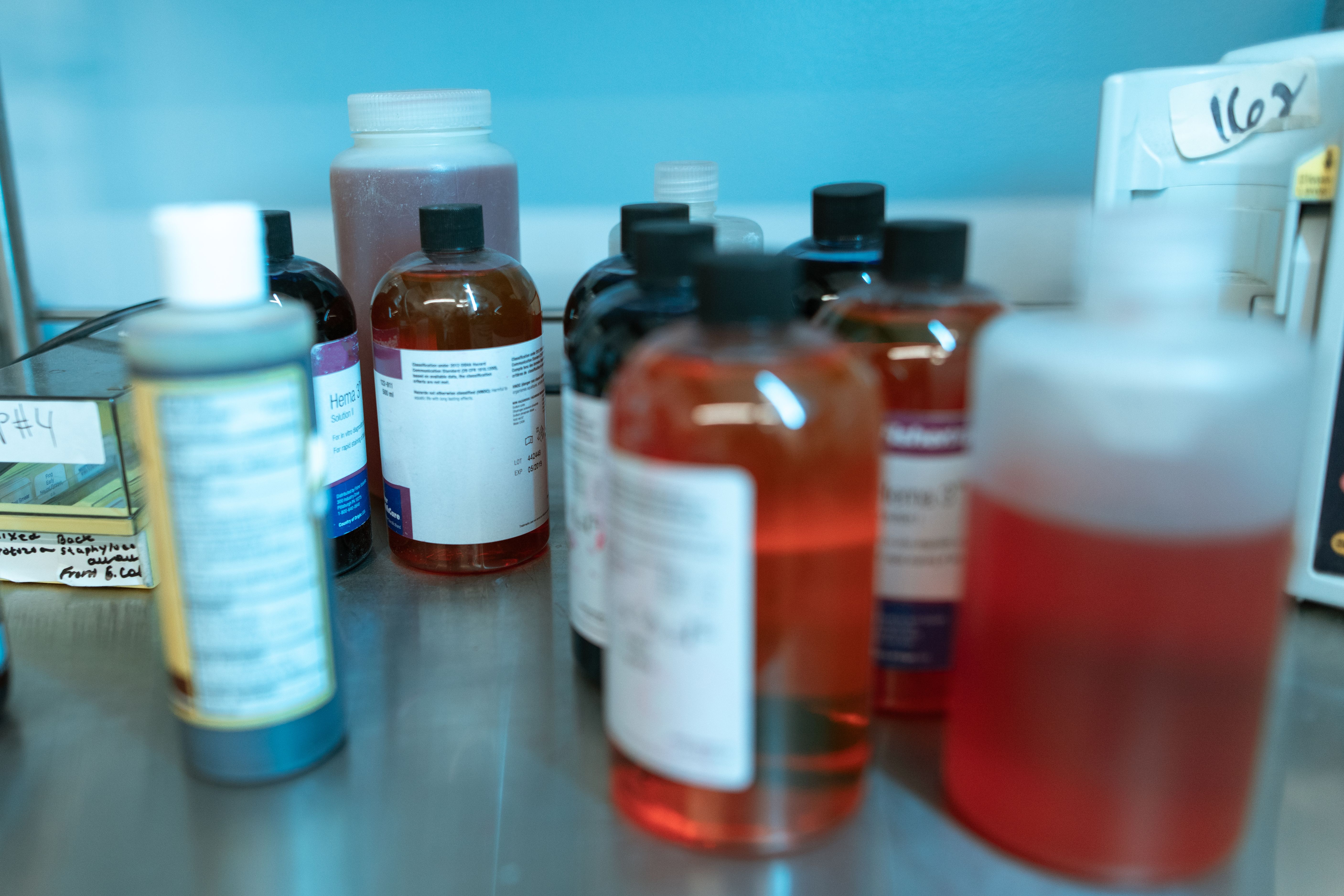 Close-up of various labeled chemical bottles on a lab bench, illustrating biochemical research.